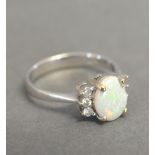 A Platinum Opal and Diamond Ring with an oval claw set opal flanked by six diamonds within a