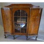 An Early 20th Century Burr Walnut Queen Anne Style Serpentine Bookcase with a central arched glazed
