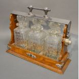 An Early 20th Century Oak and Silver Plated Tantalus with three cut glass decanters with stoppers