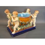 A Majolica Jardiniere in the form of a Large Basket with Putti and Foliate Swags upon a