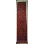 A North West Persian Woollen Runner with central medallions within an all over design upon a red and