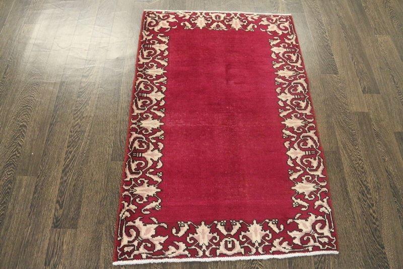 A North West Persian Woollen Rug of plain design with a cream scroll border, 132 x 86 cms