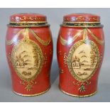 A Pair of Tole Ware Small Covered Canisters with gilded bow and ribbon decoration upon a red and