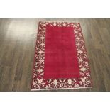 A North West Persian Woollen Rug of plain design with a cream scroll border, 132 x 86 cms