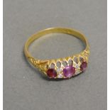 A 15ct. Yellow Gold Ruby and Diamond Band Ring set three rubies and four diamonds within a pierced