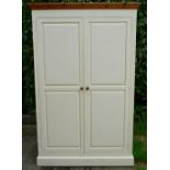 A Painted Pine Two Door Wardrobe with a moulded cornice above two panel doors raised upon a