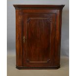 A George III Mahogany Hanging Corner Cupboard, the moulded cornice above a panelled door enclosing