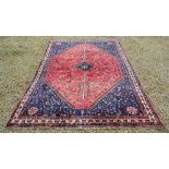 A North West Persian Woollen Carpet with a Central Medallion within an All Over Design upon a Red,