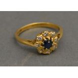An 18ct. Yellow Gold Diamond and Sapphire Set Cluster Ring with a central Sapphire surrounded by