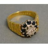 An 18ct. Yellow Gold Diamond and Sapphire Cluster Ring with a central diamond surrounded by