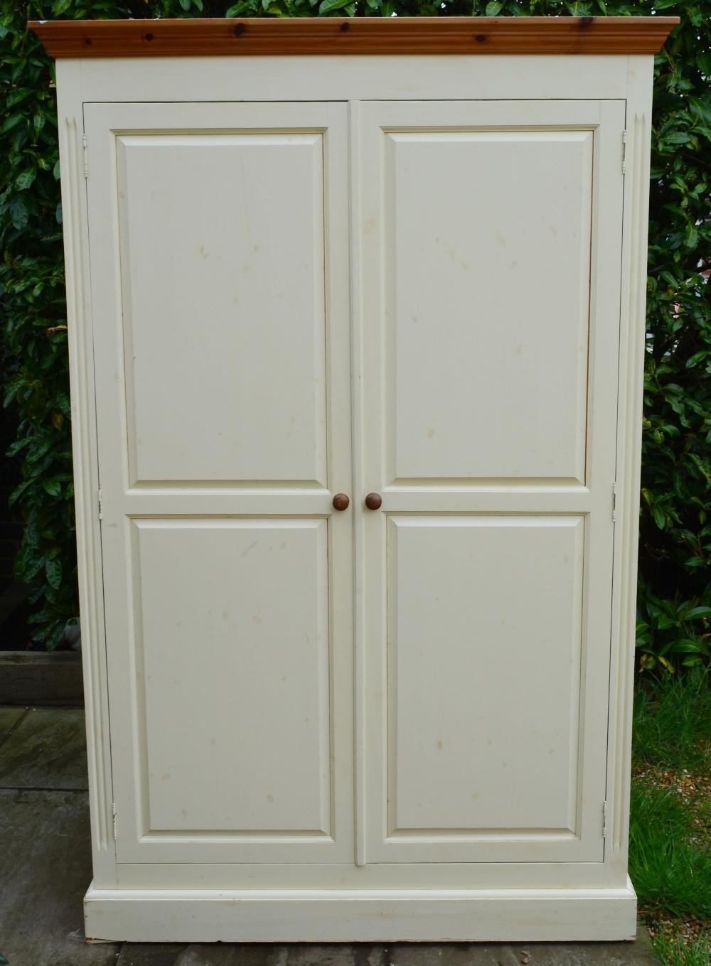 A Painted Pine Two Door Wardrobe with a moulded cornice above two panel doors raised upon a