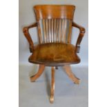 An Edwardian Mahogany Revolving Office Armchair, with a spindle back above a shaped panel seat