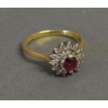 An 18ct. Yellow Gold Ruby and Diamond Cluster Ring set with a central ruby surrounded by diamonds