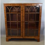 A Mahogany and Walnut Bookcase, the moulded top above two astragal glazed doors enclosing shelves