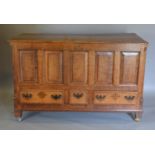 A George III Oak Mule Chest, the hinged top above a five panel front and three drawers with brass