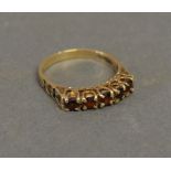 A 9ct. Yellow Gold Garnet Set Ring with five garnets within a pierced setting