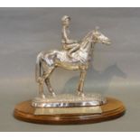 A London Silver Model in the form of a Jockey on a Racehorse upon oval wooden plinth, 22.5 cms tall,