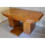 An Art Deco Walnut Extending Dining Table, the moulded top above twin end supports with extra