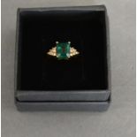 A 9ct. Gold Emerald and Diamond Ring with a rectangular emerald claw set flanked by twelve diamonds