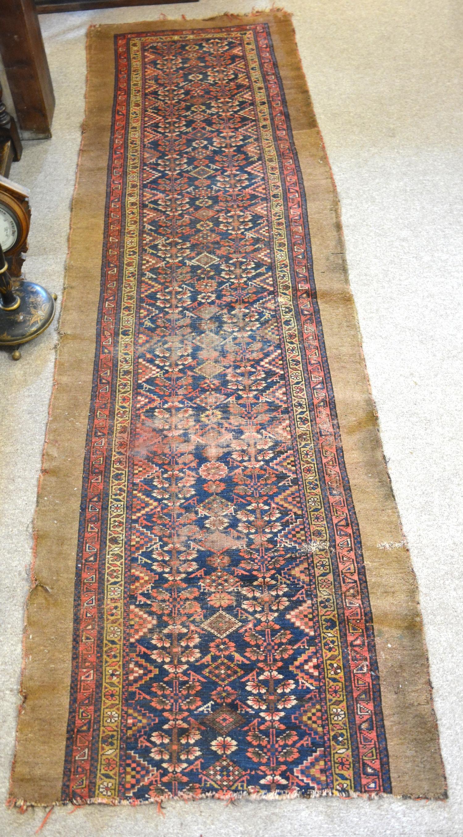 A North West Persian Woollen Runner with an all over design upon a red, blue and cream ground within