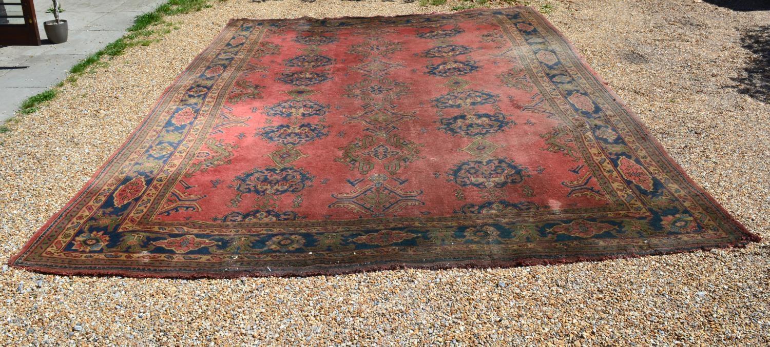 A Large Turkish Woollen Carpet with three rows of guls upon a red, blue and cream ground within