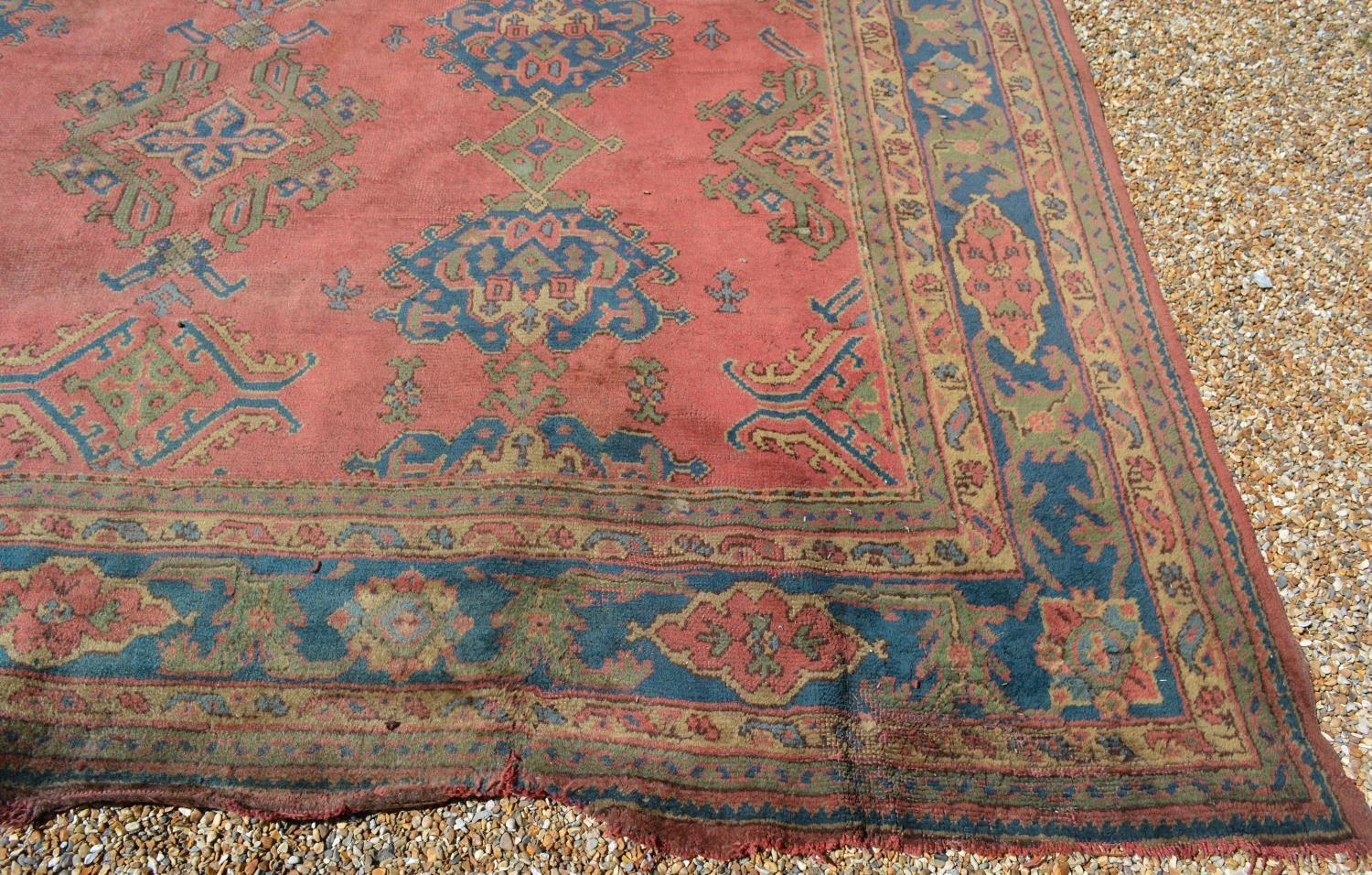 A Large Turkish Woollen Carpet with three rows of guls upon a red, blue and cream ground within - Image 2 of 6