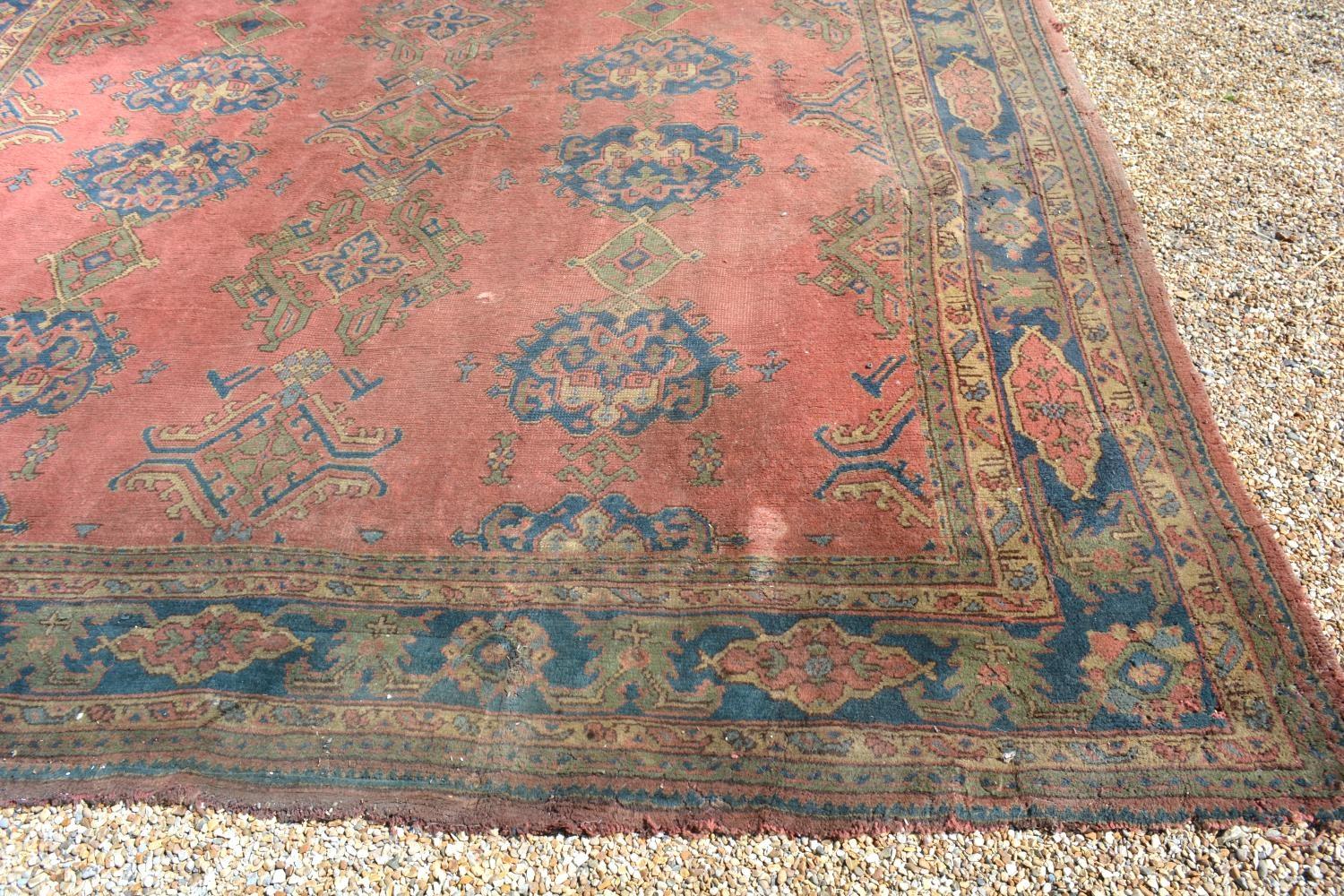 A Large Turkish Woollen Carpet with three rows of guls upon a red, blue and cream ground within - Image 4 of 6