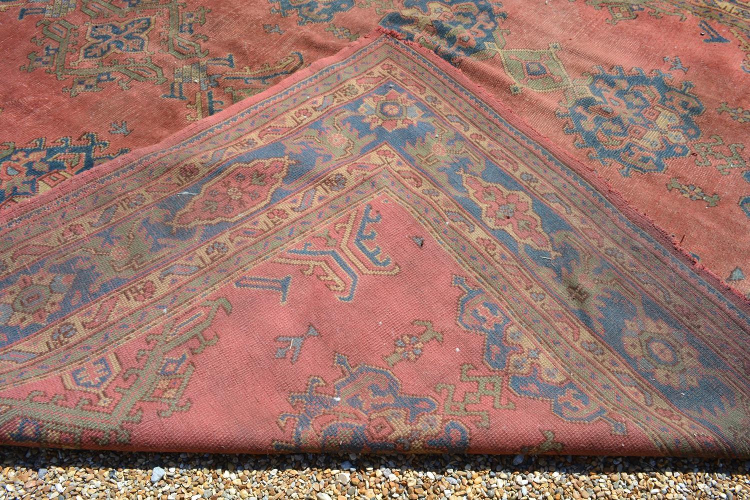 A Large Turkish Woollen Carpet with three rows of guls upon a red, blue and cream ground within - Image 6 of 6