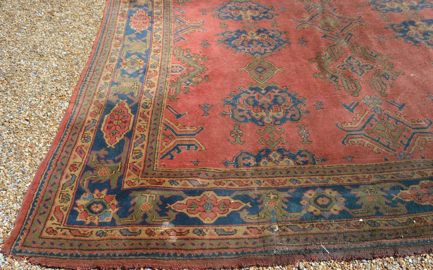 A Large Turkish Woollen Carpet with three rows of guls upon a red, blue and cream ground within - Image 5 of 6