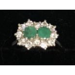 An 18ct. White Gold Double Emerald and Diamond Cluster Ring, set with two emeralds surrounded by