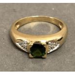 A 9ct. Gold Dress Ring set green stone flanked by diamond shoulders