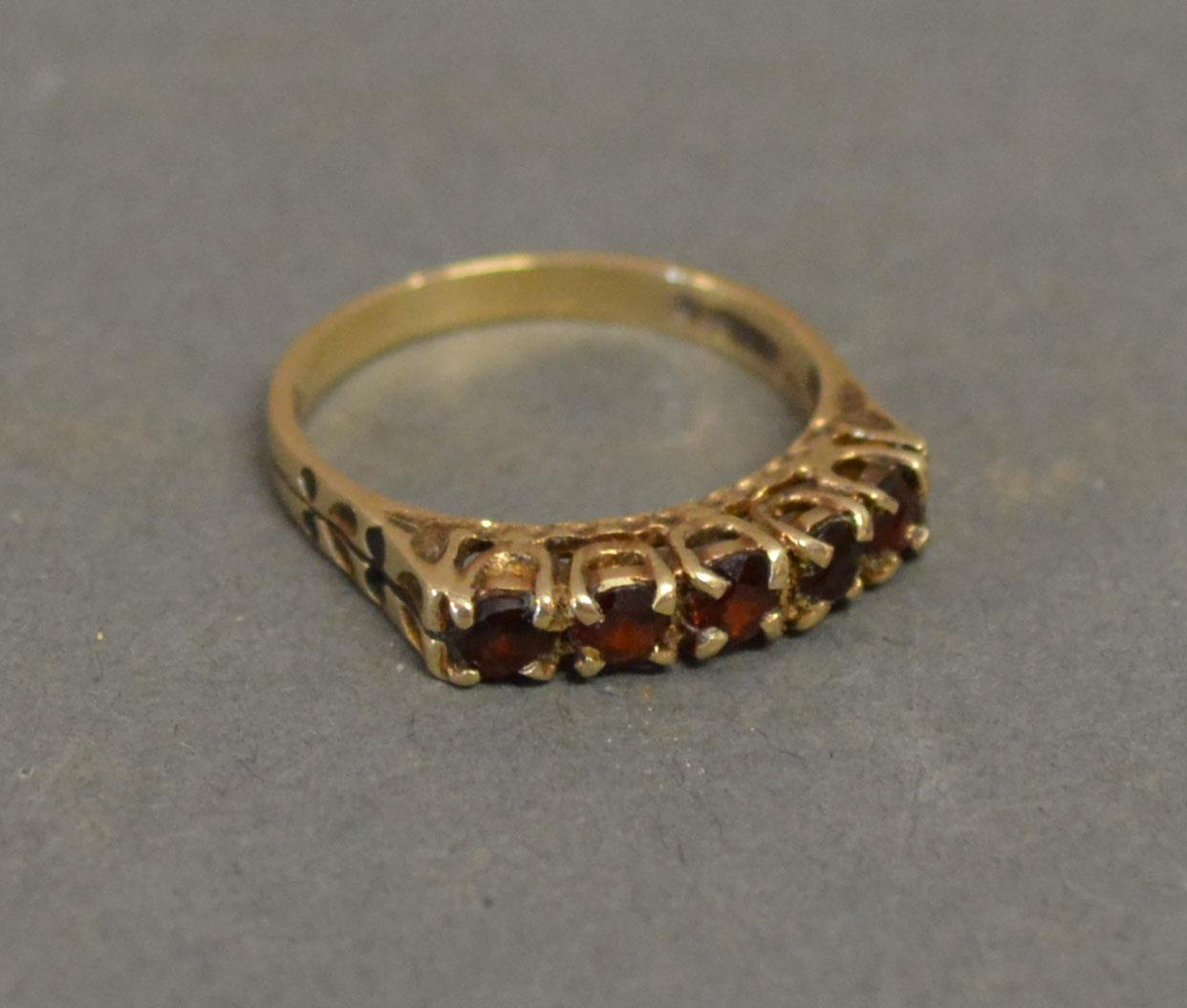 A 9ct. Yellow Gold Garnet Set Ring with five garnets within a pierced setting