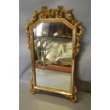 A French Gilt Framed Wall Mirror with a pierced carved cresting and scroll corner mounts, 93 cms