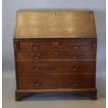 A George III Oak Bureau, the fall front enclosing drawers and pigeon holes with a central drawer