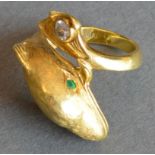 An 18ct. Gold Ring In The Form Of A Dolphine with emerald eyes and a single diamond to the tail,