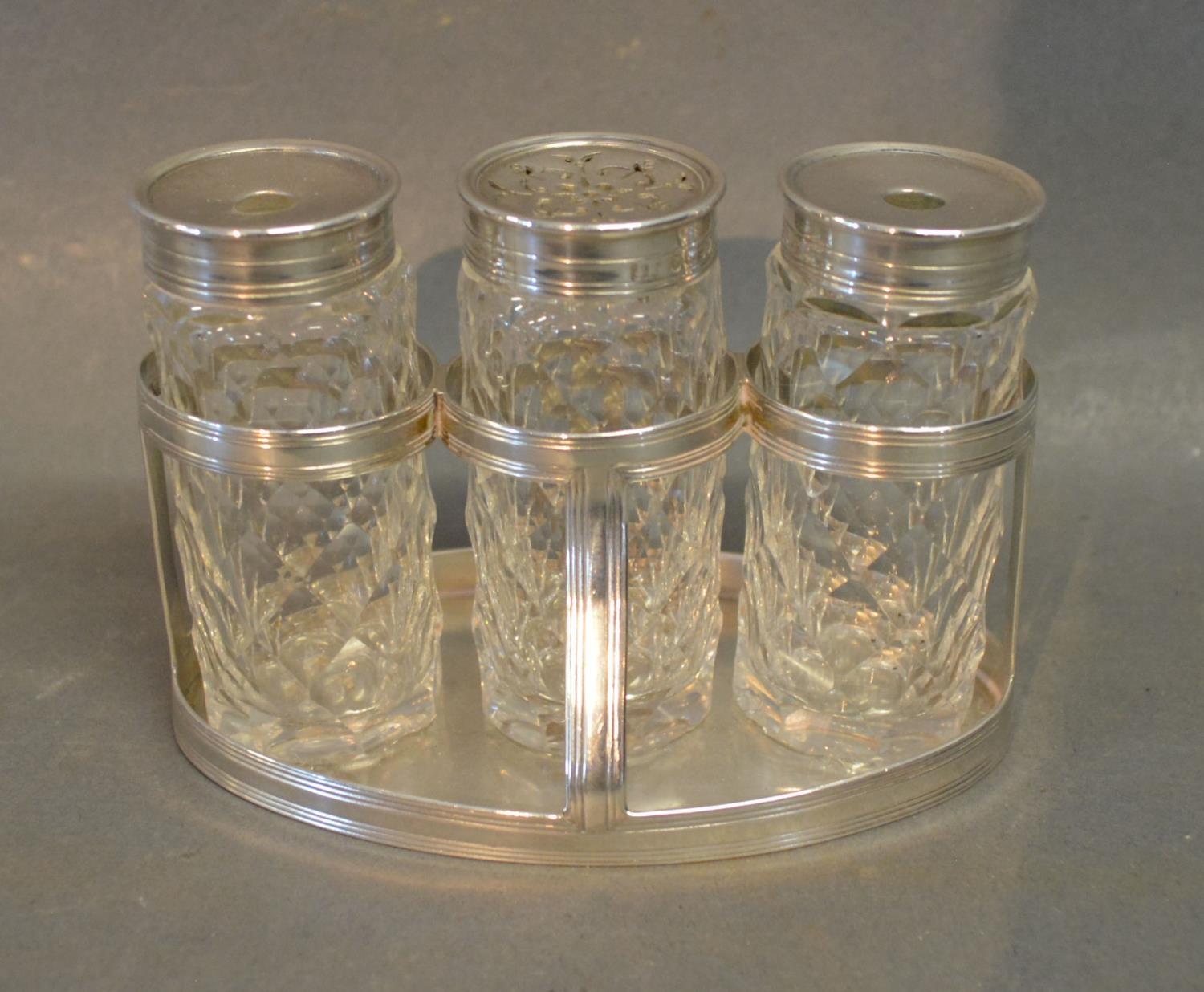 A George III Silver Desk Set, the stand of oval form with three cut glass bottles to include two
