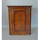 A George III Oak Hanging Corner Cabinet With A Moulded Cornice above a panel door
