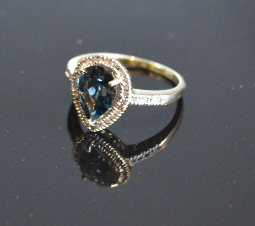 A Yellow Gold Blue Topaz And Diamond Ring set with a teardrop blue topaz surrounded by diamonds