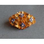 An 18ct. Gold Diamond and Sapphire Brooch of multiple flower head form, marked 750, 9.8g, 3.4cm long