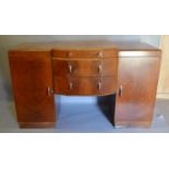 An Art Deco Walnut Pedestal Sideboard of Stylised Form with three central drawers flanked by