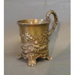 A Victorian Silver Mug decorated in relief with figures within a landscape with shaped handle raised