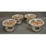 A Set Of Four Silver Plated Large Bottle Coasters with foliate shaped borders, 21cm diameter