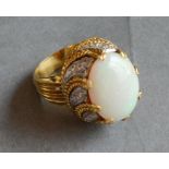 An 18ct. Gold Opal and Diamond Cluster Ring with a large oval cabochon opal above a diamond set