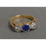 An 18ct. Gold Ring Set Central Sapphire Flanked By Diamonds within a pierced setting