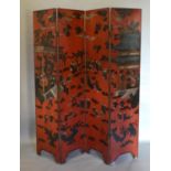 A Chinese Lacquered Four Fold Screen Decorated With Figures and buildings amongst foliage upon a red