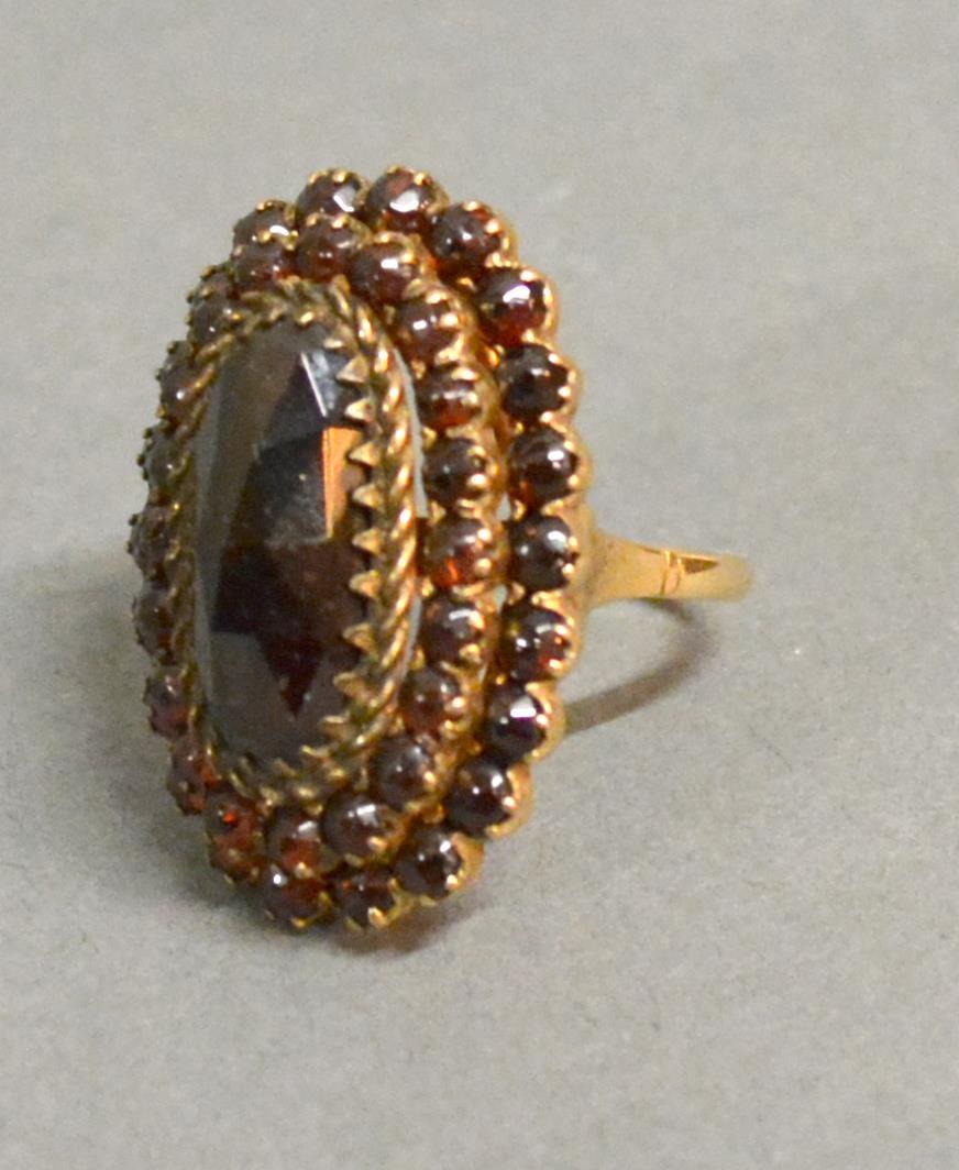 A 14ct. Gold Garnet Set Cluster Ring Of Oval Form With Tiered Rows Of Garnets