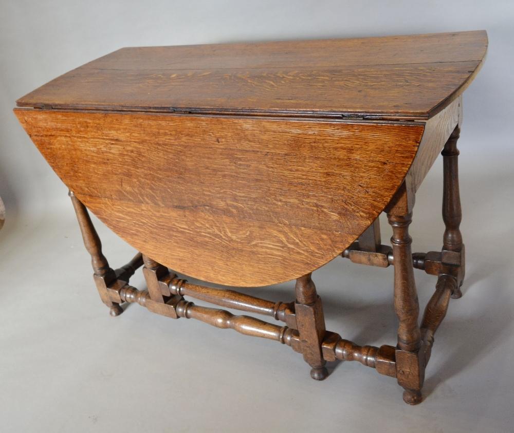 A George III Oak Oval Gate Leg Dining Table With An End Drawer, raised upon turned legs with