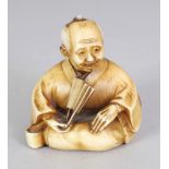 A GOOD QUALITY JAPANESE MEIJI PERIOD STAINED IVORY NETSUKE OF A SEATED MAN, holding a fan, his robes