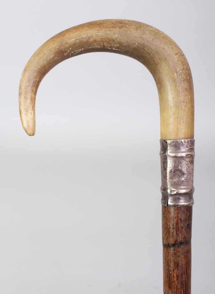 ANOTHER RHINO HORN HANDLED BAMBOO WALKING STICK, with an embossed and hallmarked silver collar,