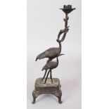 A JAPANESE MEIJI PERIOD BRONZE CANDLESTICK, cast in the form of a stork & its young, the larger bird